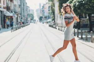 Woman happily crossing street with smartphone.
