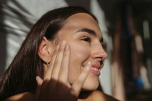 Woman smiling and applying retinoid step of her medical-grade skincare routine