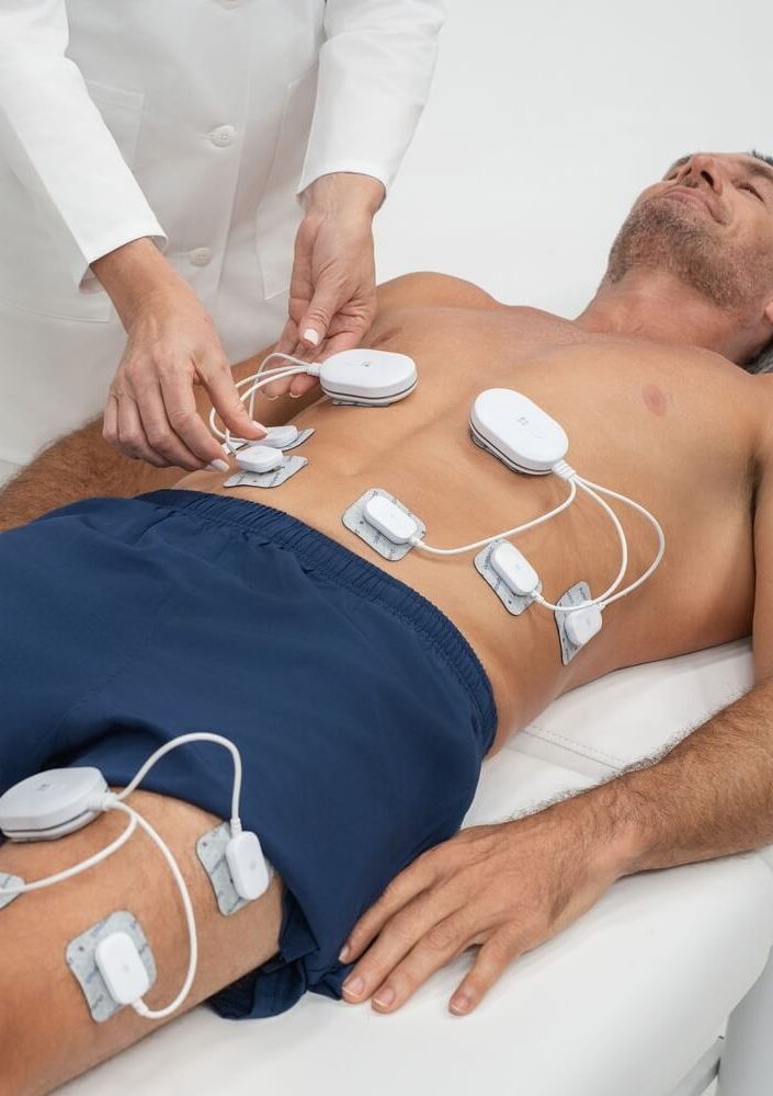 Man undergoing Pure Impact electrode therapy on abdomen and thighs