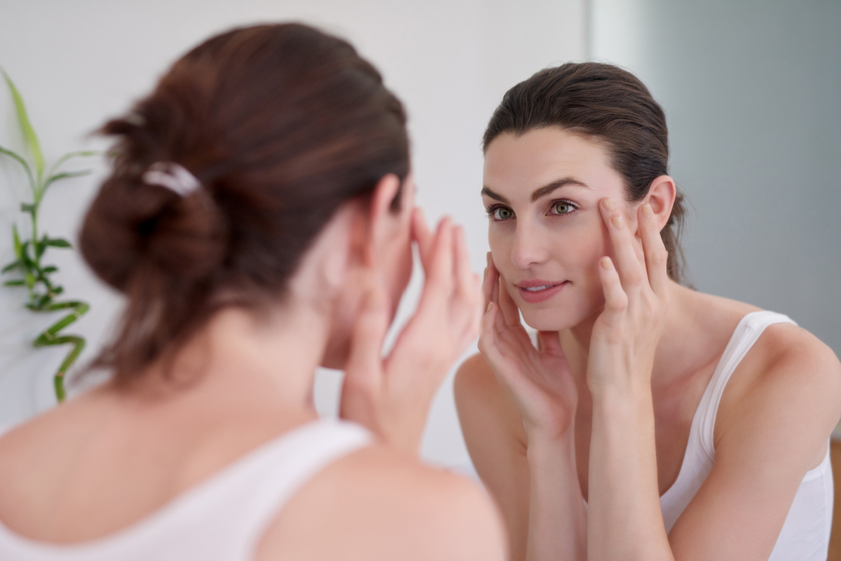 Woman looking in mirror and touching face