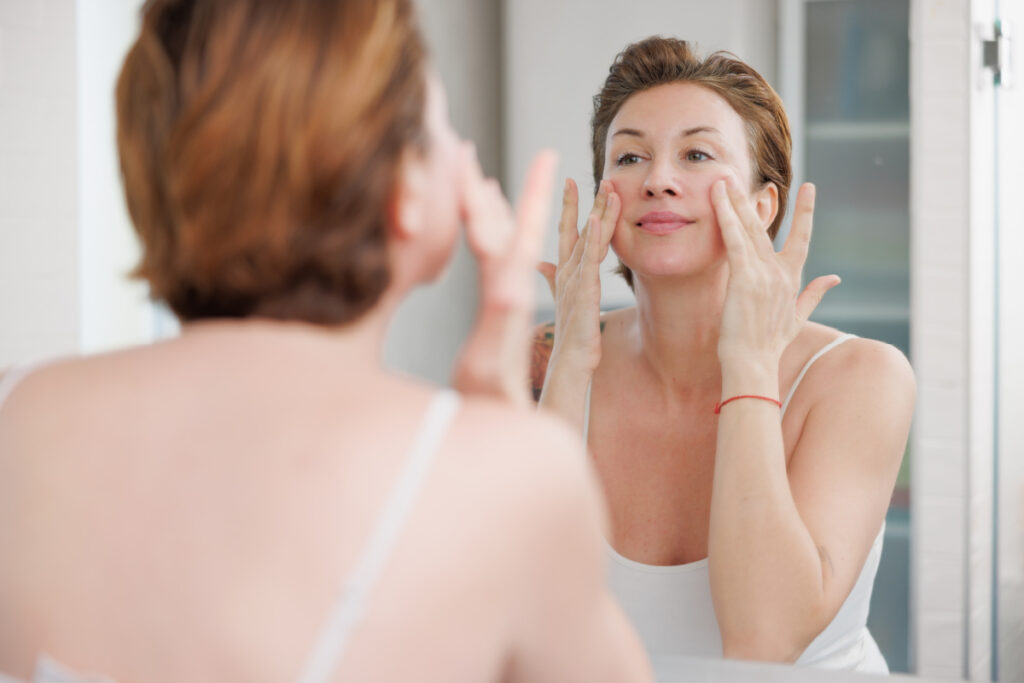 Woman looking in mirror lifting face